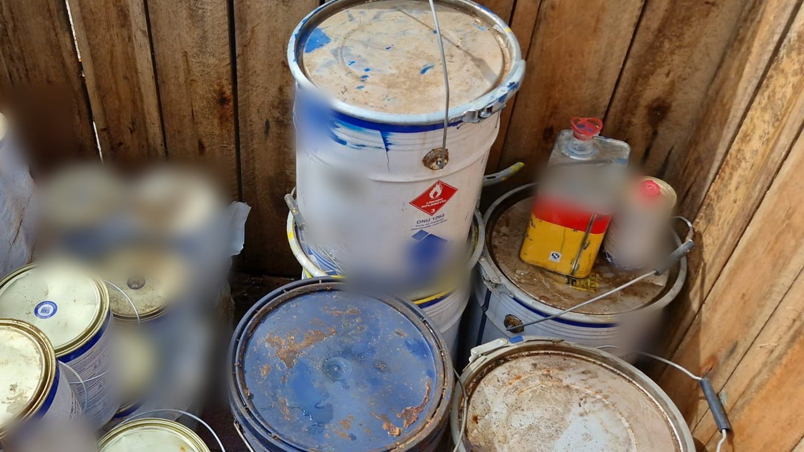 Envases de pintura y solvente almacenados sin contención en un cajón de madera
